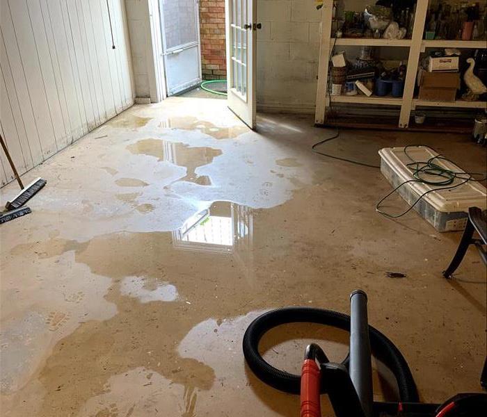 A concrete basement floor is covered in standing water