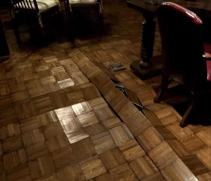 A wood floor is severely water damaged and is cupping and warped. 
